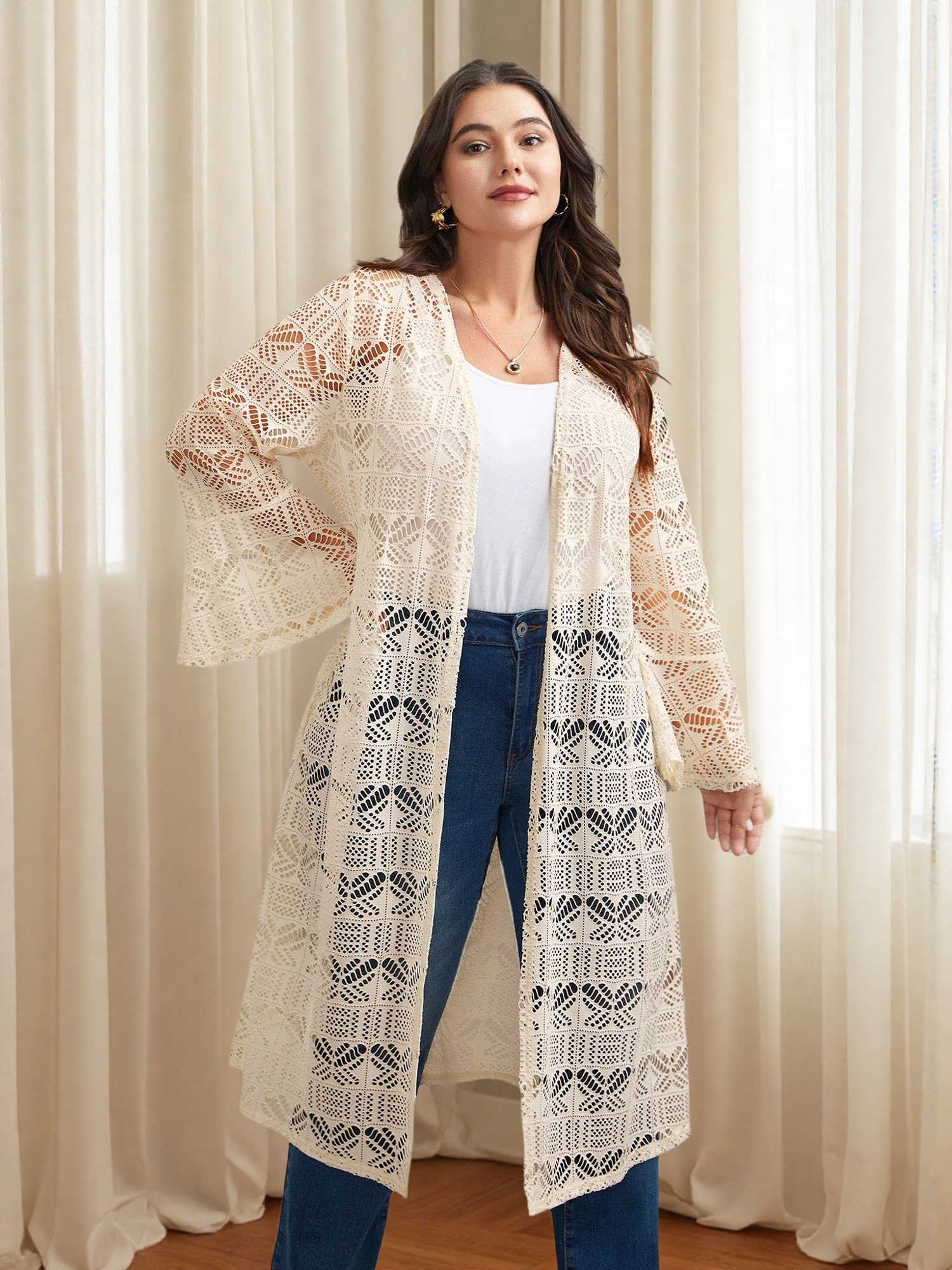 A plus-size woman wearing a cream crochet cardigan with jeans in spring