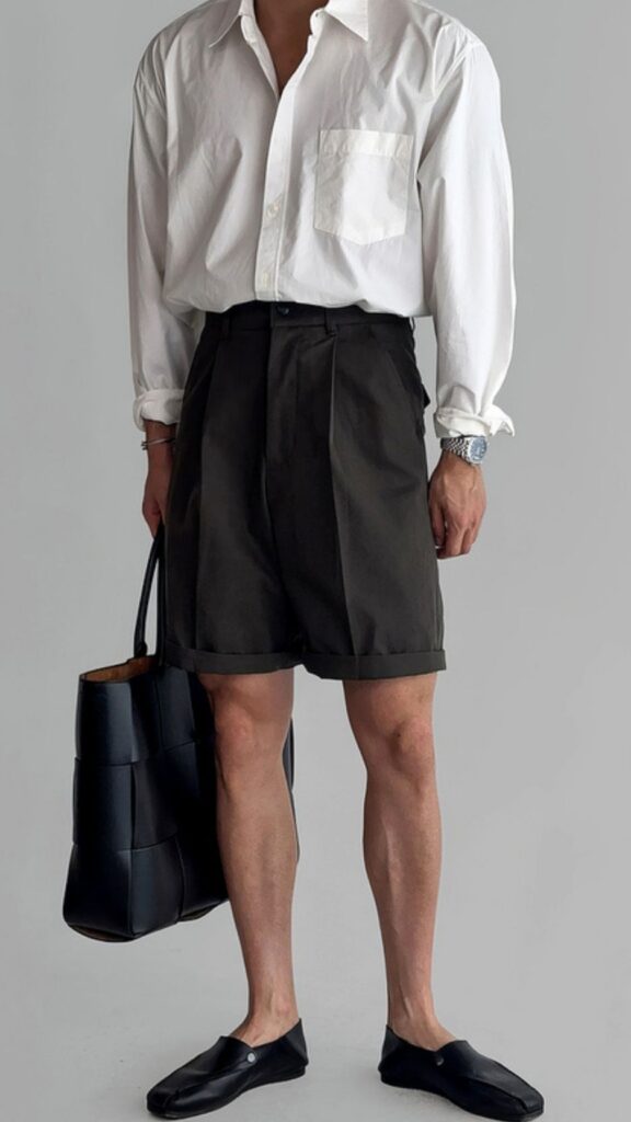 Open-neck white poplin shirt + Silver wristwatch + Black woven leather tote + Ash-charcoal tailored shorts + Minimal black leather slides