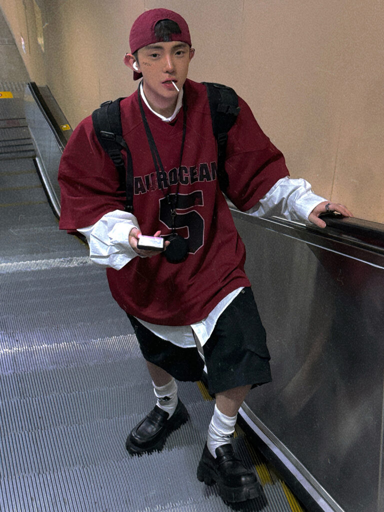 Burgundy snap-back + Oversize varsity mesh jersey + White longline poplin shirt + Black cargo shorts + Logo tube socks + Chunky lug loafers
